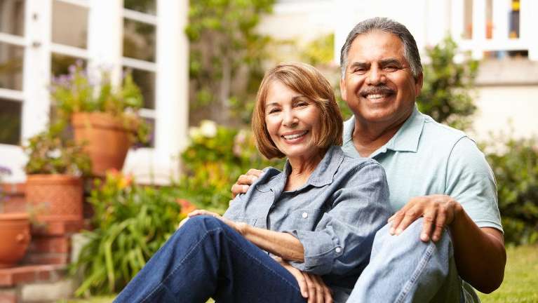 An older couple smiling outside their home | dental implants Medina