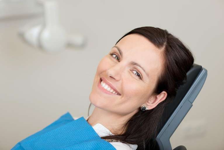Smiling woman in a dental chair, highlighting dental implants' safety and effectiveness