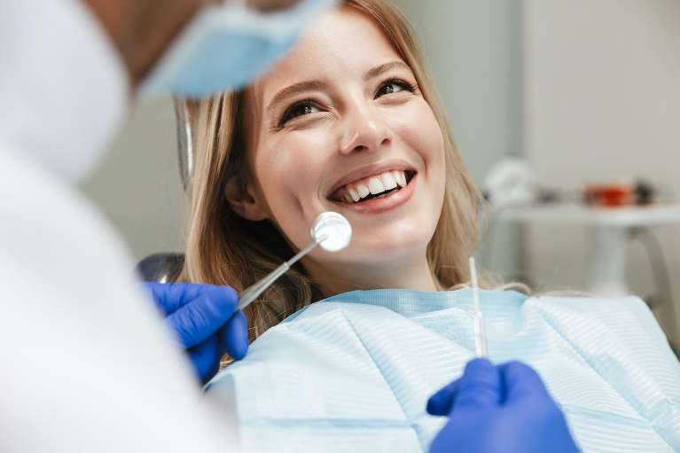 Woman smiling at dentist while sitting in a dental chair during a wisdom teeth consultation