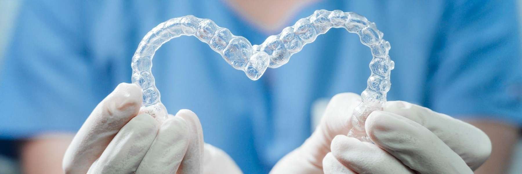 Dentist holding clear braces to demonstrate treatment option