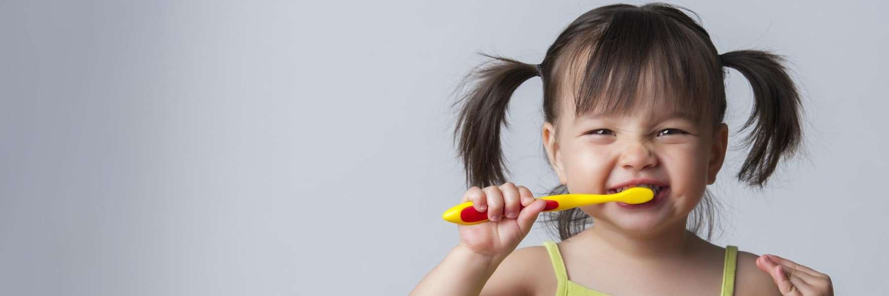 A smiling girl brushing her teeth