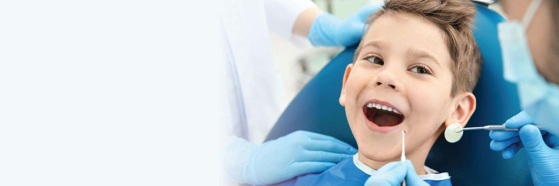 Young boy smiles during a dental checkup, emphasizing the importance of regular visits for children