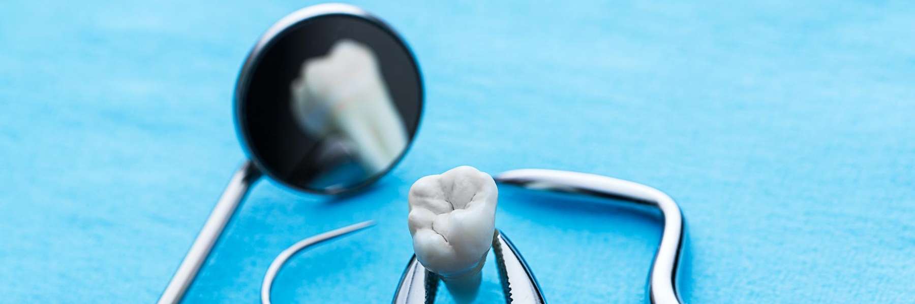 Close-up illustration of a tooth with dental tools, representing wisdom teeth removal